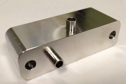 Polished machined metal block with two tube fittings